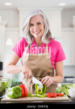 Ritratto di sorridente donna caucasica affettare verdura Foto Stock