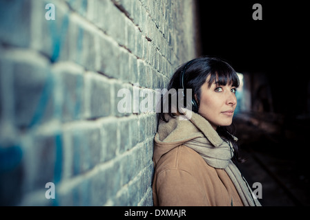 Bella giovane donna ascoltando musica le cuffie nella città inverno Foto Stock