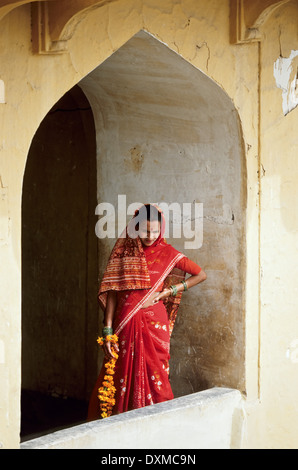 Donna indiana in un sari rosso in una finestra ad arco in Forte Amber vicino a Jaipur, India Foto Stock