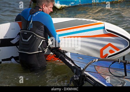 Windsurf getting impostare pronto per windsurf a barene, Poole in Marzo Foto Stock