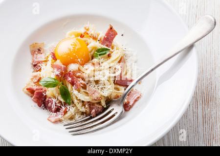 Spaghetti alla carbonara sulla piastra bianca con prosciutto e tuorlo Foto Stock