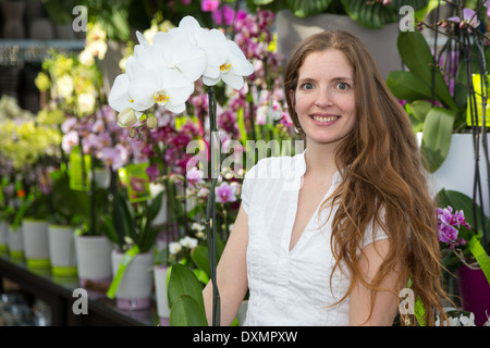 Il cliente nel negozio di fiori in posa con un'orchidea Foto Stock