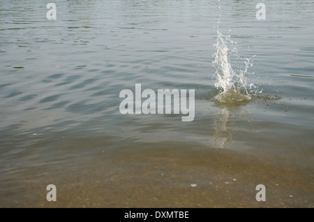 Schizzi di acqua come roccia urta il fiume Foto Stock