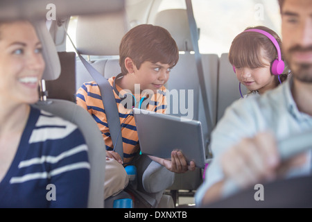 Fratello e Sorella di condivisione digitale compressa nel sedile posteriore della macchina Foto Stock