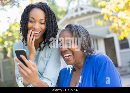 Madre e figlia guardando al telefono cellulare e ridere Foto Stock