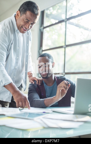 Padre e figlio discutendo la documentazione al laptop Foto Stock