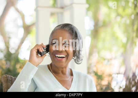 Entusiasta il senior donna parlando al telefono sul portico Foto Stock