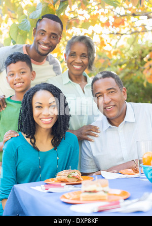 Ritratto di sorridere multi-generazione famiglia mangiare il pranzo al patio tabella Foto Stock