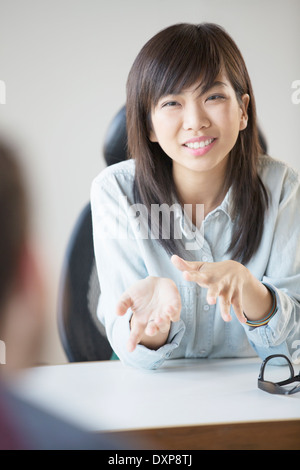 Sorridente imprenditrice gesticolando in riunione Foto Stock