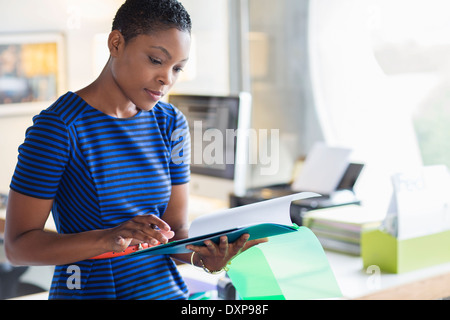 Imprenditrice seria revisione di documenti cartacei in ufficio Foto Stock