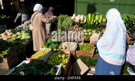 Le donne musulmane shopping alimentare acquistare frutta e verdura presso un negozio di stallo in Whitechapel High Street Market East London, England Regno Unito KATHY DEWITT Foto Stock