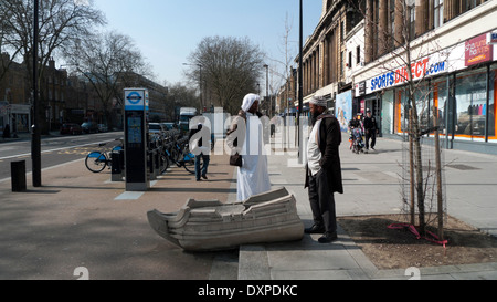 Due uomini musulmani nella conversazione accanto alla barca in calcestruzzo su Mile End Road Whitechapel East London, Regno Unito KATHY DEWITT Foto Stock