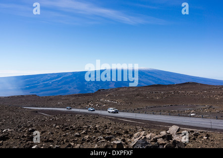 Sulle vetture di Mauna Kea summit road. Mauna Loa in background. Big Island delle Hawaii. Foto Stock