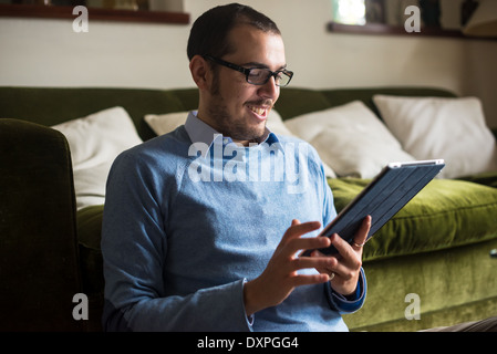 Elegante business multitasking uomo multimediale utilizzando dispositivi a casa Foto Stock