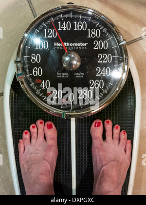 Donna di peso se stessa su una bilancia da bagno, STATI UNITI D'AMERICA Foto Stock