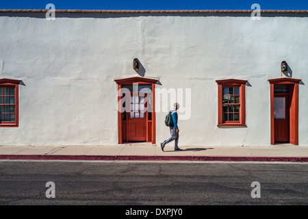 Uomo che indossa un pacchetto al giorno a piedi un passato coloniale spagnolo edificio nella città vecchia di Tucson, Arizona, Stati Uniti. Foto Stock