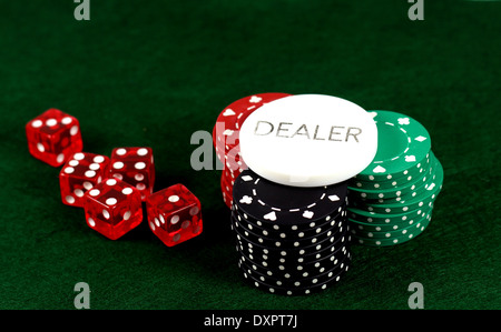 Verde, rosso e nero poker chips con il concessionario pulsante e dadi su uno sfondo verde Foto Stock