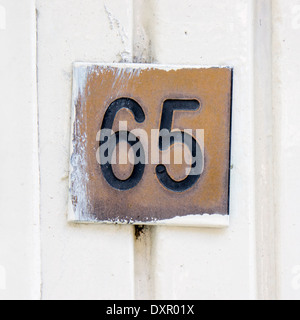 Numero di casa sessanta cinque incise in un marrone targa in ottone Foto Stock