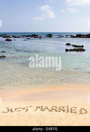 Appena sposato scritto in sabbia su una spiaggia bellissima, blu chiaro onde in background Foto Stock