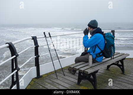 Saltburn dal mare, North Yorkshire, Inghilterra del nord est, Regno Unito. 29 marzo, 2014. Escursionista in fase di riscaldamento con una bevanda calda su Saltburn il molo vittoriano in una fredda e nebbiosa mattina di sabato sulla costa nord est. Con temperature gomitata 20 gradi in alcune parti del Regno Unito, un freddo vento est mantenuto a temperature di circa 7 gradi a Saltburn. Credito: ALANDAWSONPHOTOGRAPHY/Alamy Live News Foto Stock