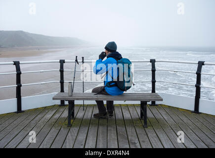 Saltburn dal mare, North Yorkshire, Inghilterra del nord est, Regno Unito. 29 marzo, 2014. Escursionista in fase di riscaldamento con una bevanda calda su Saltburn il molo vittoriano in una fredda e nebbiosa mattina di sabato sulla costa nord est. Con temperature gomitata 20 gradi in alcune parti del Regno Unito, un freddo vento est mantenuto a temperature di circa 7 gradi a Saltburn. Credito: ALANDAWSONPHOTOGRAPHY/Alamy Live News Foto Stock