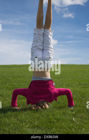 Ragazza giovane facendo capo sorge su una collina di erba Foto Stock