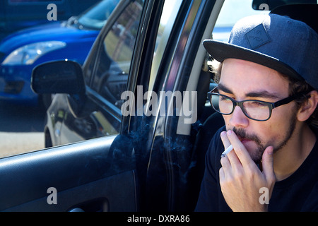 Giovane uomo inalazione di una sigaretta presso il parcheggio della Fiera di organico in Amon Foto Stock