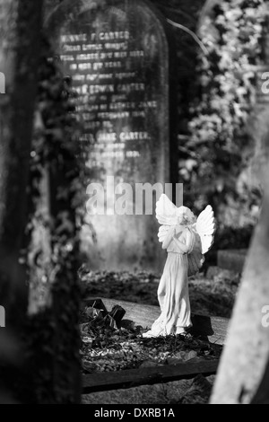 Piccolo angelo statua su una tomba nel cimitero di Highgate, London, Regno Unito Foto Stock