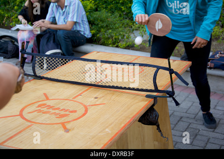 Il giovane e la giovane donna giocando a ping pong in un piccolo tavolo di legno. Foto Stock