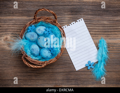 Cesto in Vimini pieno di blu uova di quaglia con preavviso la carta Foto Stock