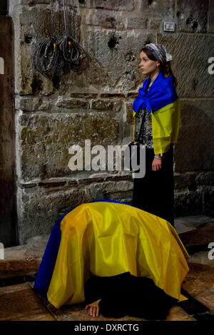 Pellegrini cristiani provenienti da Ucraina avvolto con la bandiera ucraino in preghiera nella chiesa del Santo Sepolcro di Gerusalemme in Israele Foto Stock