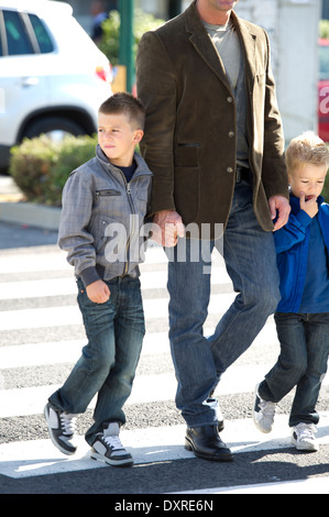 Padre e figli camminando per strada Foto Stock