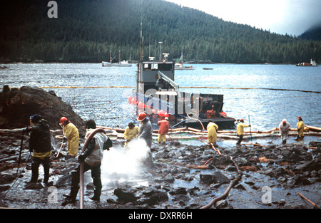 Lavoratori sbuffo di vapore rocce e lavi giù il litorale imbevuto di petrolio greggio dal perde petroliera Exxon Valdez dopo arenamento sul Bligh Reef in Prince William Sound fuoriuscita di almeno 11 milioni di galloni di petrolio greggio nelle acque incontaminate Marzo 28, 1989 in Prince William Sound, Alaska. Foto Stock