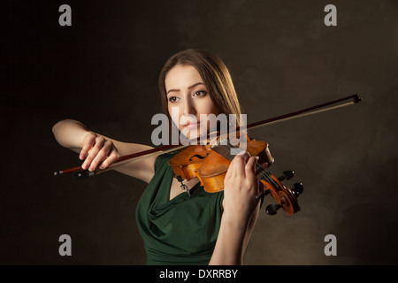 Bella giovane donna suona il violino su sfondo nero Foto Stock