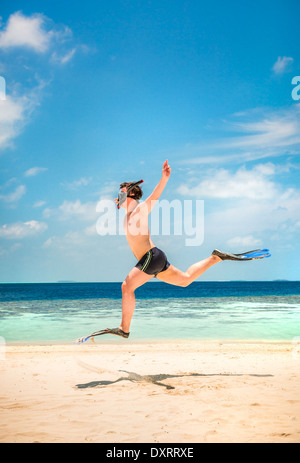 Funny Man jumping in pinne e maschera. Casa vacanze su una spiaggia tropicale a isole delle Maldive. Foto Stock