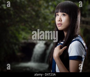 Carino da studentessa cinese con cascata in background Foto Stock