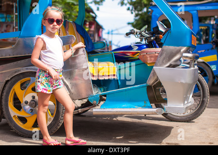 Bambina vicino a trasporto locale threecycles nel paese asiatico Foto Stock