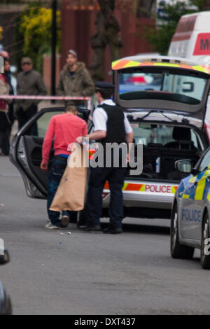 Londra, 30 marzo 2014. Il suo apparentemente bloodtained jersey ora in una busta di prova, un possibile sospetto è introdotto in un veicolo di polizia come ha incontrato funzionari di polizia ufficiali indagare su ciò che è stato descritto come un "molto grave assalto' in Cricklewood. Credito: Paolo Davey/Alamy Live News Foto Stock