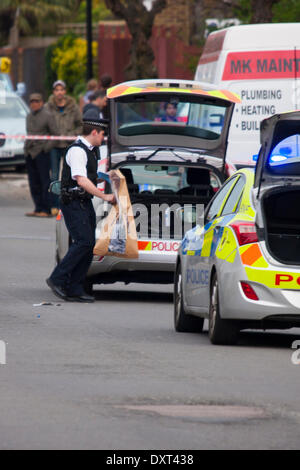 Londra, 30 marzo 2014. Ha incontrato un funzionario di polizia pone un sospetto topheld in una busta di prova nel retro di un veicolo di polizia come essi indagare su ciò che è stato descritto come un "molto grave assalto' in Cricklewood, a nord di Londra. Credito: Paolo Davey/Alamy Live News Foto Stock