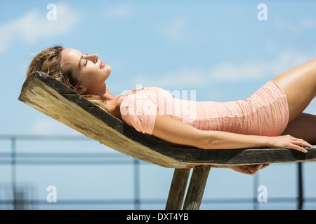 Donna in abito a prendere il sole sulle sdraio Foto Stock