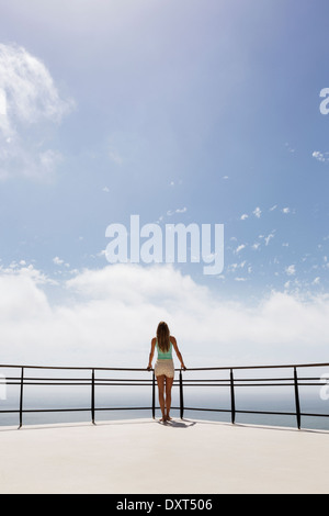 Donna in piedi sul balcone con vista sul mare Foto Stock