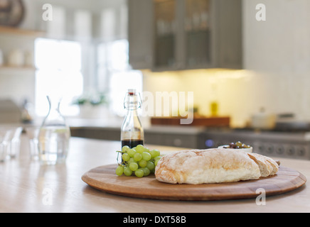 Baguette, aceto balsamico e uva sulla tavola di legno in cucina Foto Stock