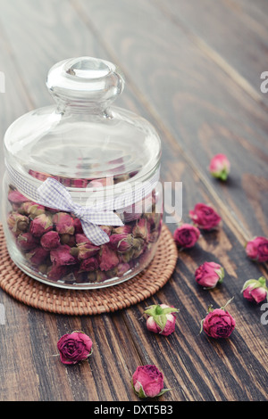 Tea rose fiori in vaso di vetro su sfondo di legno Foto Stock