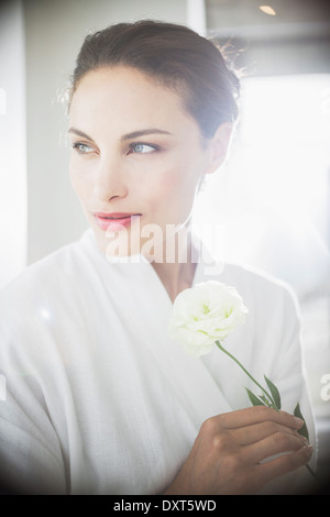 Close up della donna in accappatoio tenendo la rosa bianca Foto Stock