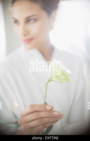 Close up della donna in accappatoio tenendo la rosa bianca Foto Stock
