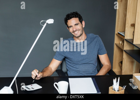 Ritratto di uomo sorridente alla scrivania in ufficio in casa Foto Stock
