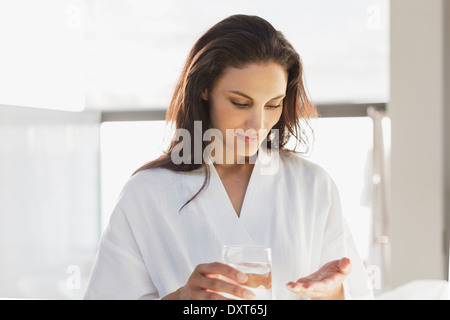 Donna in accappatoio prendendo medicinali nella stanza da bagno Foto Stock