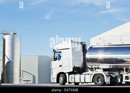 Autista del camion parcheggio in acciaio inox autocisterna per il latte al di fuori di insilato torre di storage Foto Stock