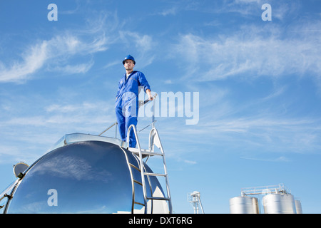 Lavoratore in piedi su acciaio inox autocisterna per il latte Foto Stock