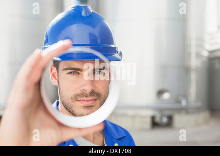 Ritratto di lavoratore cerca attraverso il tubo di metallo Foto Stock